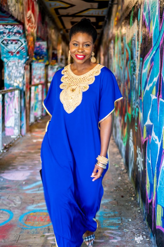 How to Wear an African Boubou, tips featured by top Atlanta fashion blogger, Hurry in Time:  lady in blue boubou dress outside walking under a graffiti bridge