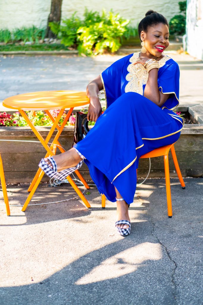 How to Wear an African Boubou, tips featured by top Atlanta fashion blogger, Hurry in Time: lady in blue boubou dress sitting in a orange chair outside