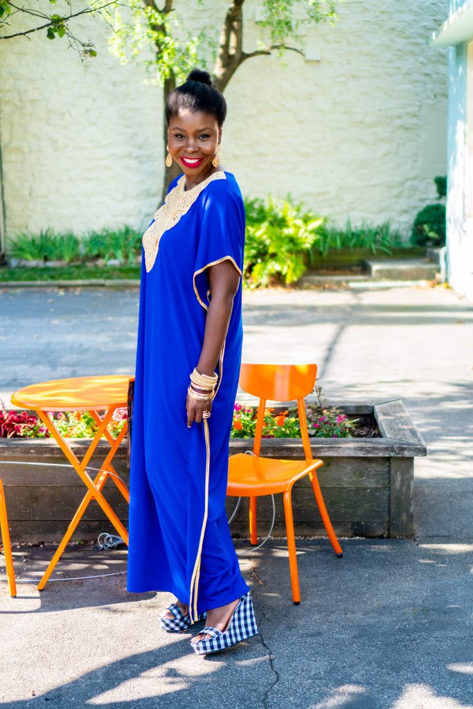 How to Wear an African Boubou, tips featured by top Atlanta fashion blogger, Hurry in Time: lady in blue boubou dress standing by an orange table 