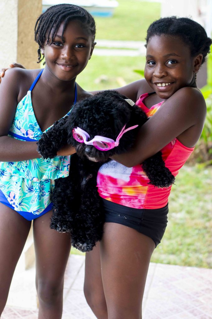 two girls holding a black dog