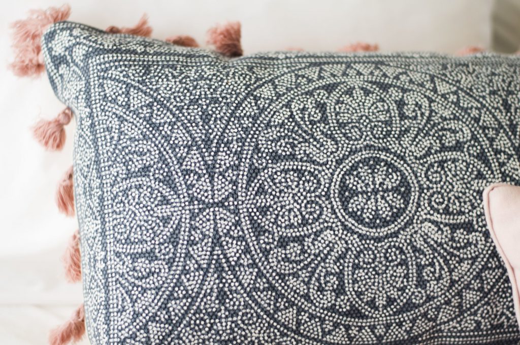 Blue Paisley Pillow on a bed with pink tassels 