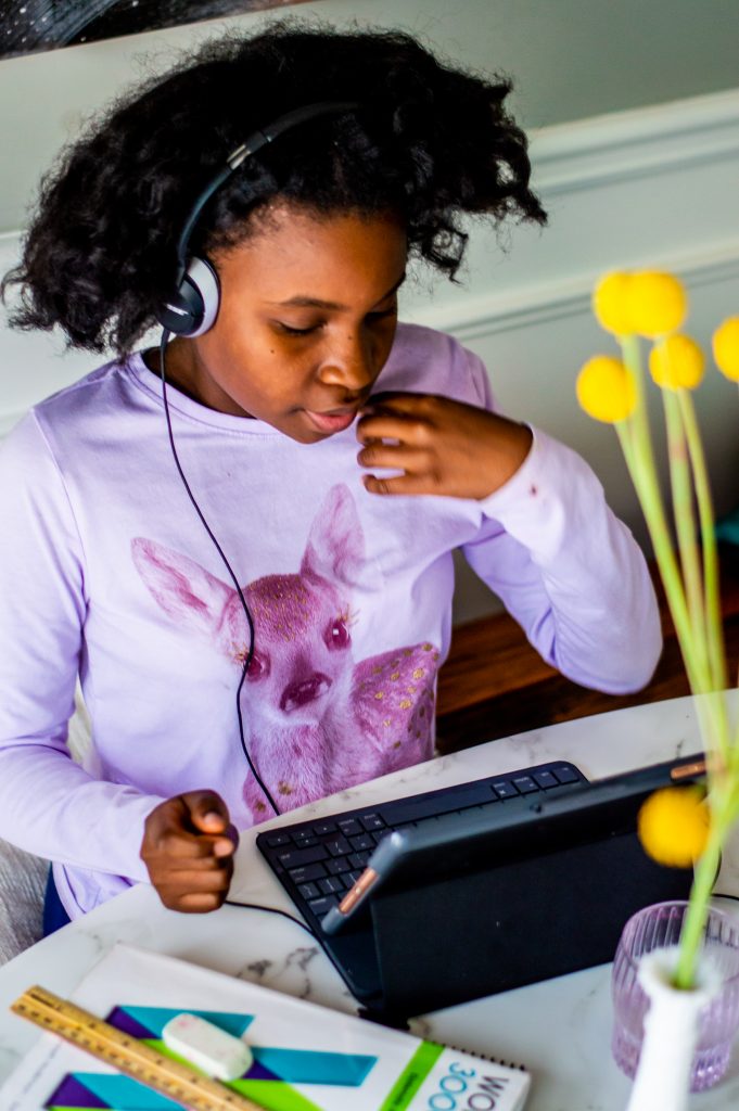 Girl with headphones on looks at a computer5 Tips for Working From Home and Homeschooling During Self-Quarantine featured by top Atlanta lifestyle blogger, Hurry in Time: 