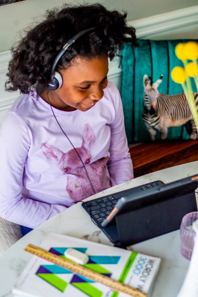 5 Tips for Working From Home and Homeschooling During Self-Quarantine featured by top Atlanta lifestyle blogger, Hurry in Time: Girl with headphones on laughing looking at a computer