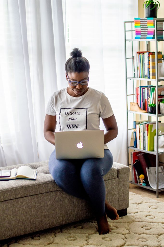 5 Tips for Working From Home and Homeschooling During Self-Quarantine featured by top Atlanta lifestyle blogger, Hurry in Time: Woman sitting on a ottoman typing on a laptop