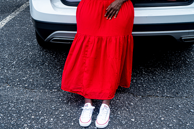 Woman in a red dress sitting on the back of a white car