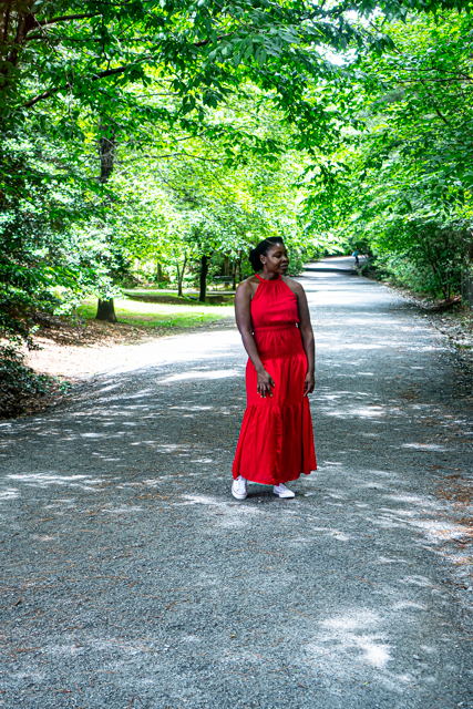 Woman in a red dress stopped on a trail